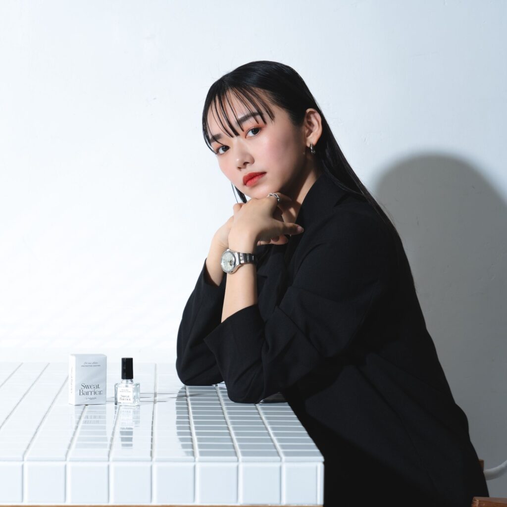 Sweat Barrierが置かれたテーブルに座り「これはお勧めよ」という表情でこちらを見ている女性。