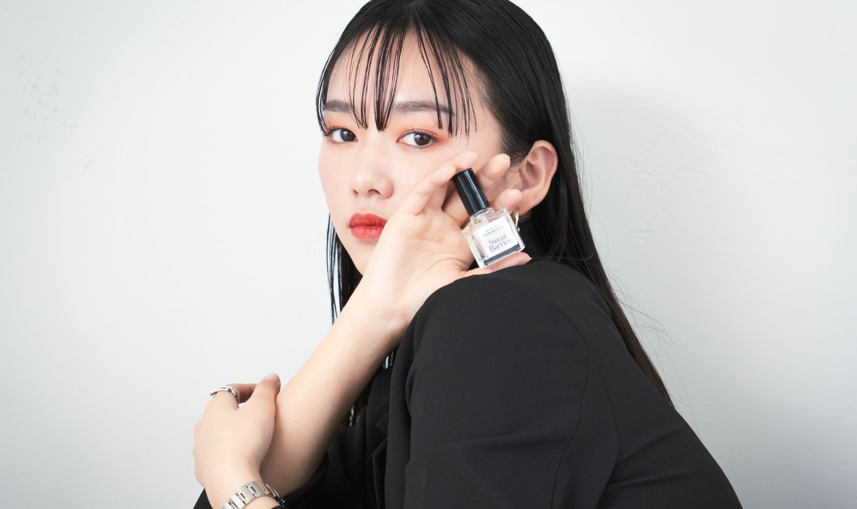Sweat Barrierを顔の前にかざし、その特徴を説明するようにこちらに話しかけている女性。
